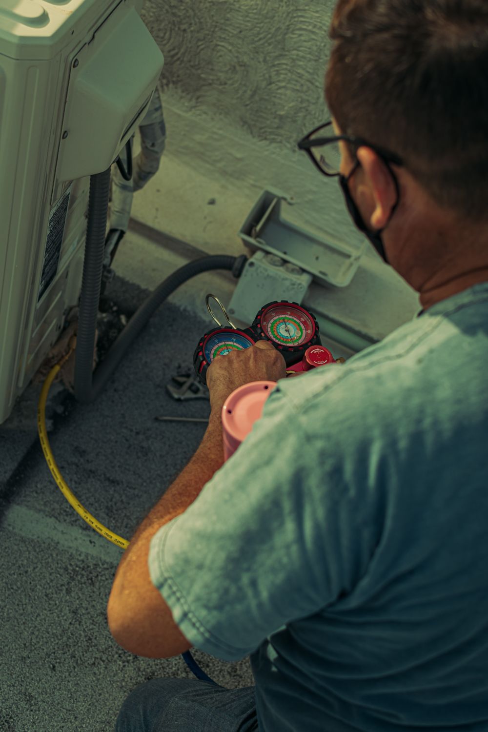 Technician using refrigerant gauges to service an outdoor heat pump