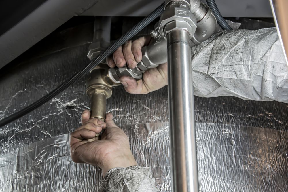 Hands connecting a brass fitting beneath a sink