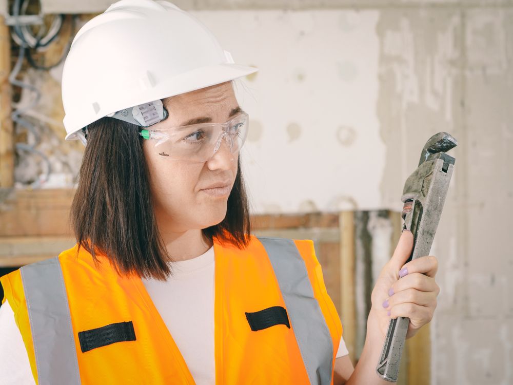 Technician in safety gear holding a pipe wrench