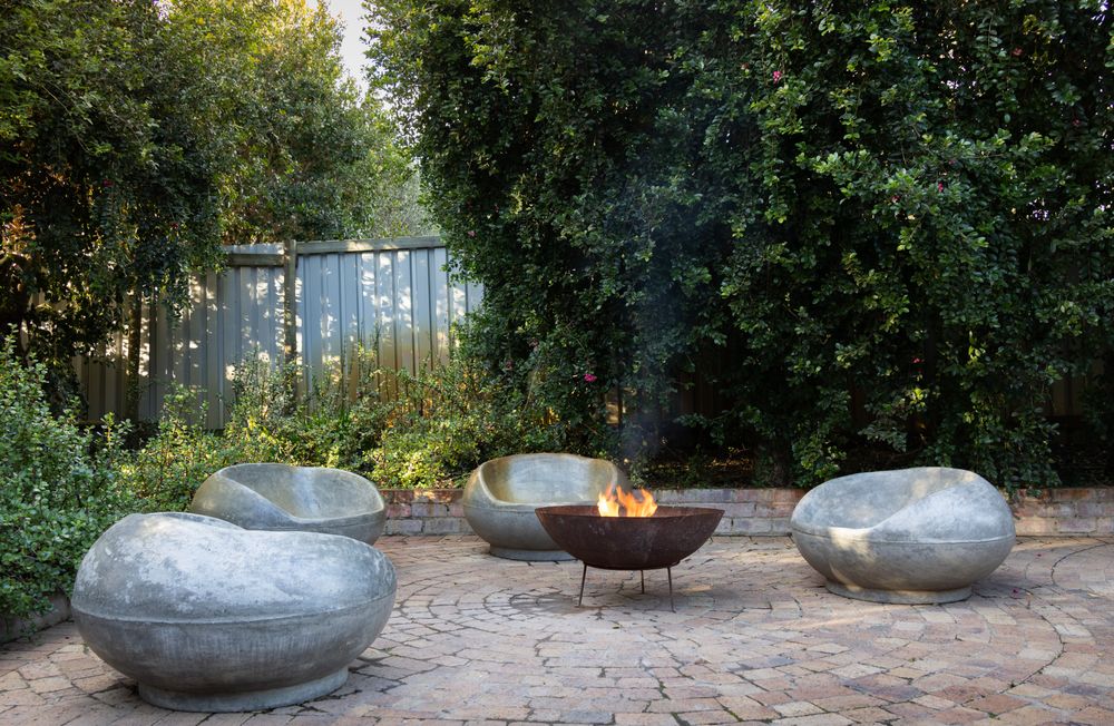 Curved stone lounge seating around a backyard fire pit