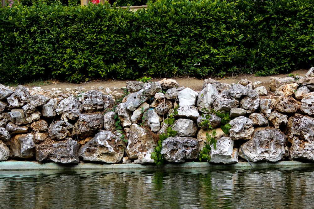 Dry-stacked stone retaining wall along a garden pond