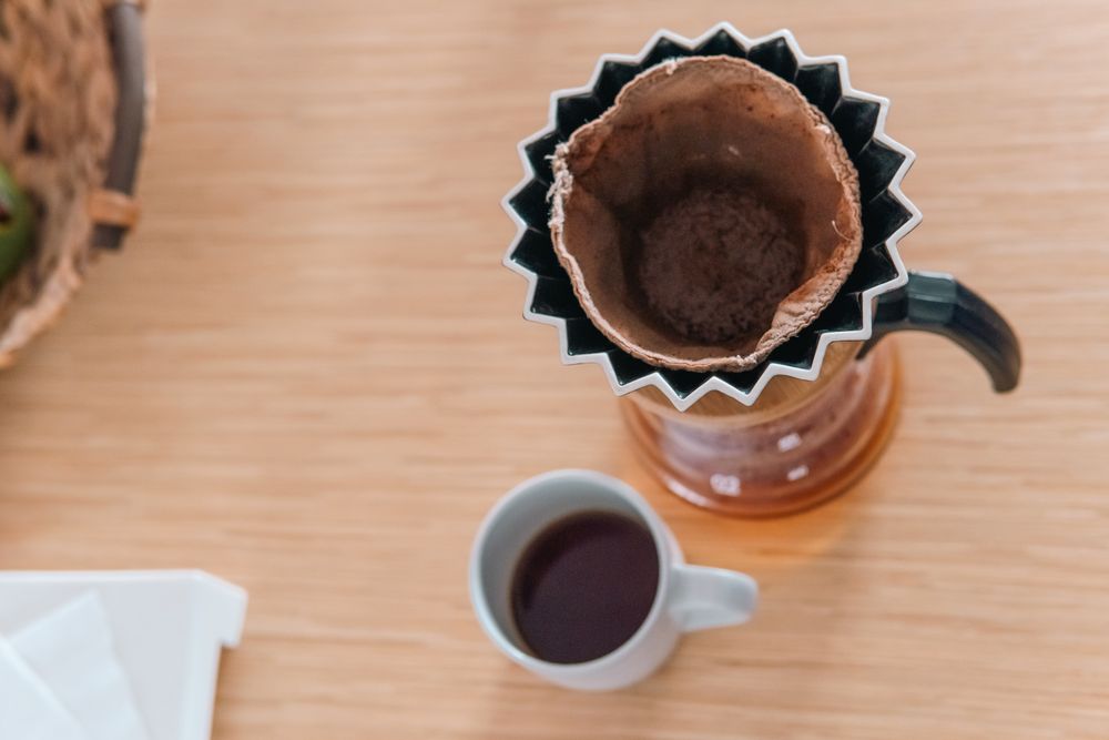 Overhead view of a used pour-over filter beside a finished cup of coffee