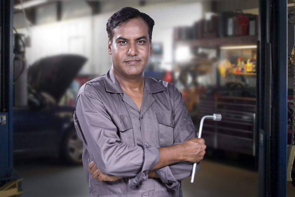 Malik Osei, lead technician at Overdrive Auto Works, working under a vehicle