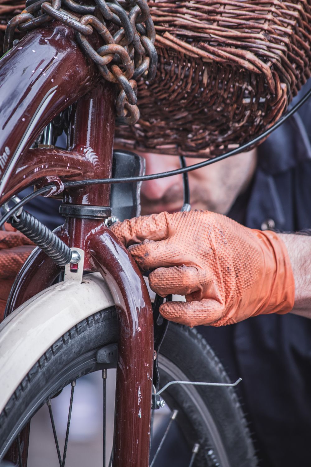Close-up of a mechanic's gloved hand repairing a vintage bicycle fork