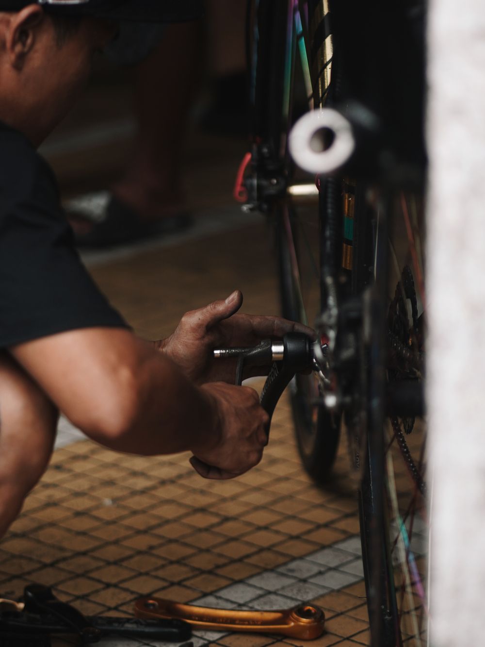 Mechanic kneeling to adjust a bicycle crank and chain
